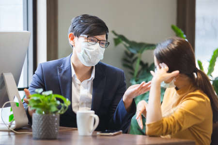 asian business people with wearing hygienic mask prophylactic manager talking in meeting work room planning.の写真素材