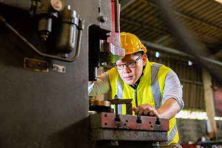 Asian engineering man wearing uniform safety worker perform maintenance in factory working machine...