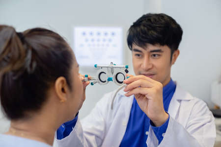 Close up messbrille eye test glasses in a hand of optometrist with blur women background. Ehecking...