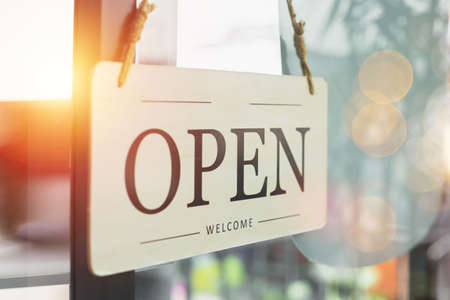 Sign wooden open hanging on front glass door of cafe. welcome entrance shop.