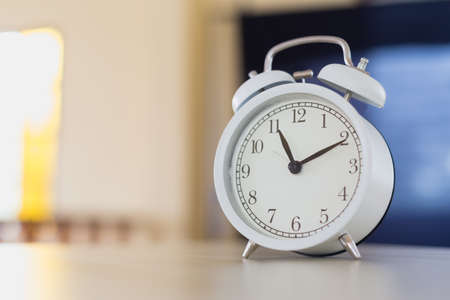 white alarm clock analog with bell on table in the morning inside house. equipment hurry wake up...