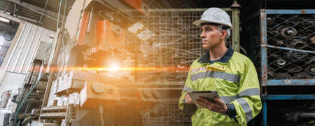 Man engineer industry heavy worker wearing hardhat and holding tablet, double exposure at machine area in factory, factory industrial concept.の写真素材