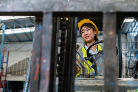 women wear safety helmet happy smiling looking at camera driver forklift warehouse in factory....