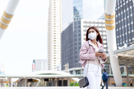 Asian women red hair wearing medical face mask for prevent dust and protect  virus pandemic, standing in business city center.の写真素材