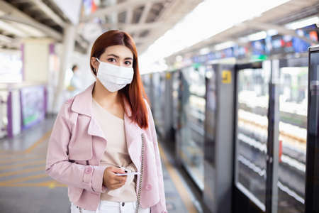 asian beautiful woman wearing medical mask for prevent dust and infection virusà¸¡ standing in train station transit system public.の写真素材