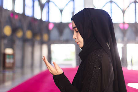 Young muslim woman in wear black dress read quran and making wish praying in mosque. make a wish and...