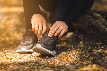 Close up man jogger ties shoes in nature park.の写真素材