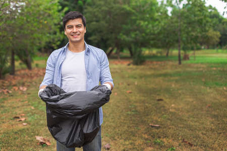 Man volunteer holding garbage bag in green park.の写真素材