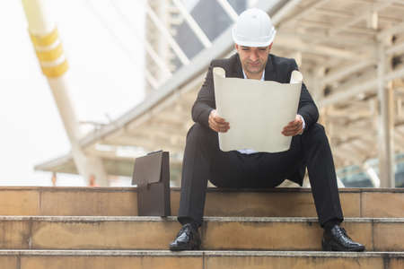 man engineer wearing safety with reading blueprint in construction site.の写真素材