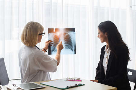 senior woman doctor and patient examining x-ray report in medical hospital.