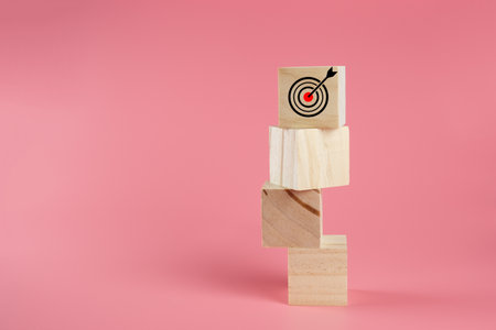 Stack wooden block cube with goal icon on pink background, successful growing business concept.