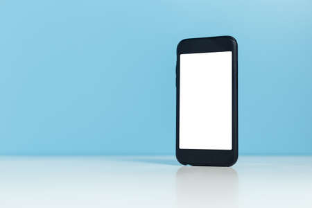Mobile phone, Smartphone white display empty on table blue background. blank touchscreen using for message media or advertising. clipping path.の写真素材