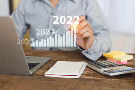 Businessman touching growth graph year 2022. stock exchange analyzing chart. information statistics...