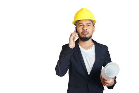 Asian engineering man wears hardhat talking telephone and holding blueprint on white background. foreman control construction.  .の写真素材