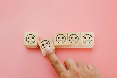hands of man finger pointing selection wooden cube blocks with happy emotion icons. personnel...