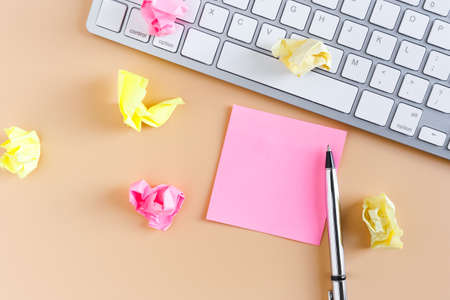 Empty sticky post note paper sheet and with computer keyboard on pink table. workspace for text top view.の写真素材