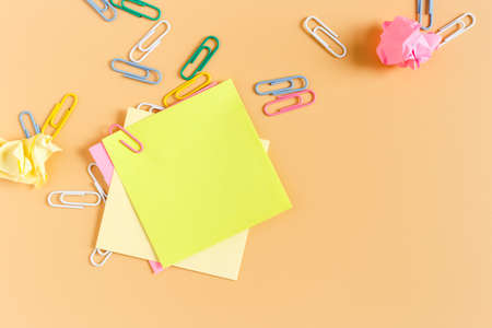 Stack empty sticky post note paper sheet with paper clip on orange background. office business...