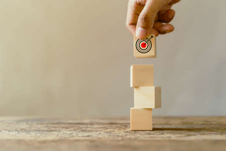 Stack wooden block cube with hand picking goal icons, successful growing business concept.の写真素材