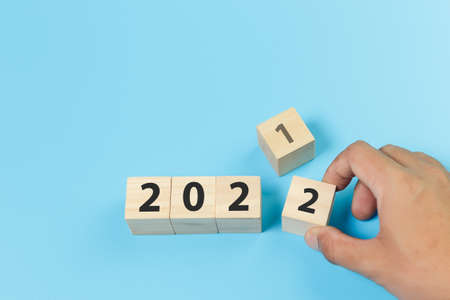woodblocks cubes number 2021 change to 2022 with hand picking blue background. new year 2021- 2022 concept.の写真素材