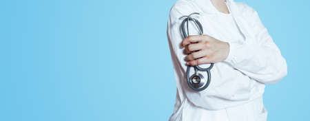 Doctor white gown uniform with stethoscope in hands blue background. cardiologist measurement. Healthcare and treatment conceptの写真素材