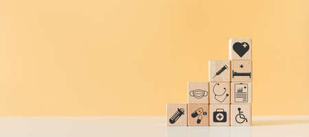 Wooden block with healthcare medical icons orange pastel background. stacking wooden cube box medical. healthcare treatment concept.の写真素材