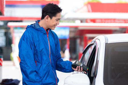 man employee gas station attendant holding card reader payment terminal and credit card for users of...
