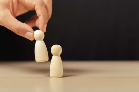Wooden figures human was chosen leadership of teamwork. man's hands are select wooden puppet to...