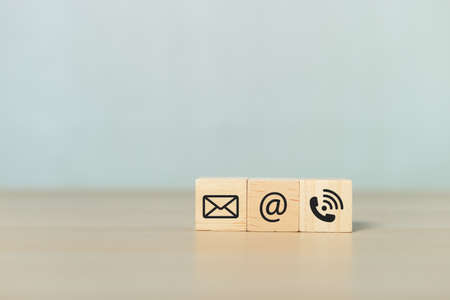 Concept of contact us. wooden cube blocks with contact icons on table. symbol of connection, email telephone and dialog box. Technology social network.の写真素材