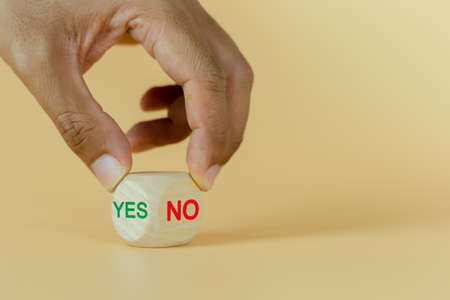 Concept of question and answer. Hand holding wooden cube block with text yes or no select choice. symbol of decision positive question and answer.の写真素材