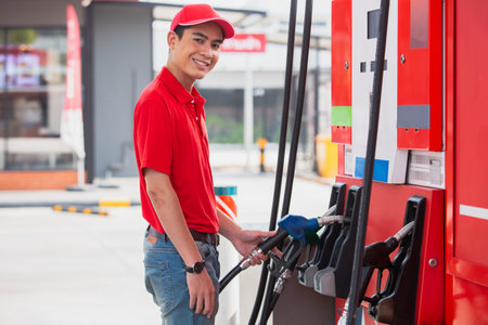 Man holding pump nozzle for service at gas station. male employee worker fueling oil car. business energy concept.の写真素材
