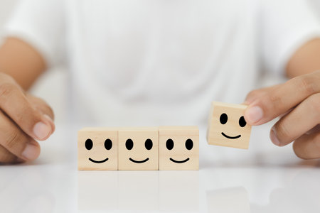 hands of man pick up selection wooden cube blocks with smile emotion icons. rating and ranking business concept.の写真素材