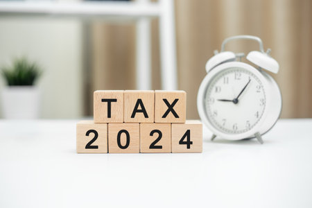 TAX 2024 message on wooden cube block on table. Taxation on sale of product. Providing services in each production process and sell goods or services, both manufactured. Value Added Tax Concept.の写真素材