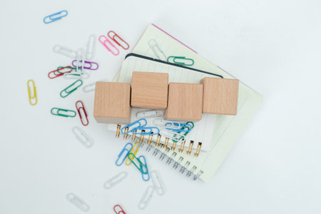 Wooden cube block empty on notebook with paper clip on white table. business object sign...