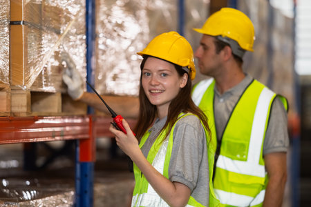 women engineer holding walkie talkie and tablet quality control standing at machine of factory warehouse. professional engineering machinery workshop.の写真素材