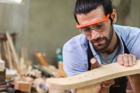 young carpenter man wearing goggles working use sandpaper for wood polishing. factory industry woodwork. craftsman professional technician handmade.の写真素材