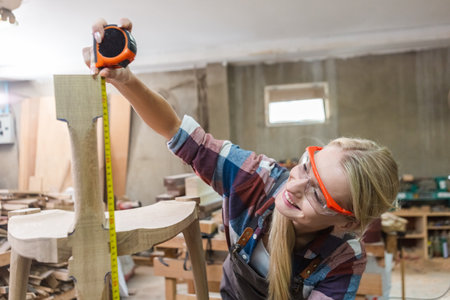 young carpenter women using measuring tape looking wood size at workspace. craftsman profession in...