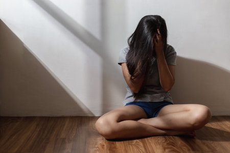 Female having depression hands covering face sitting alone on floor. she with depressed embracing knees. unhappy emotion.の写真素材
