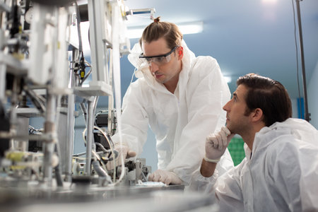 Machine staff, mask production department. Engineer wearing protective suit Inspecting quality of...
