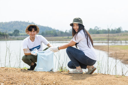 Male and female volunteers collecting garbage, conducting environmental cooperation, saving world reducing global warming, Volunteers clean plastic bag waste in natural attractions.の写真素材
