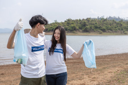 man and woman volunteers holding rubbish bags. clean up garbage in tourist attractions. Conservation and care cleanliness in nature.の写真素材