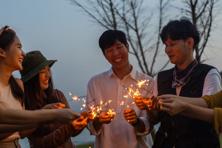 Happy friends holding fire sparkles. Group of young Travel join in fun at camping party in nature....