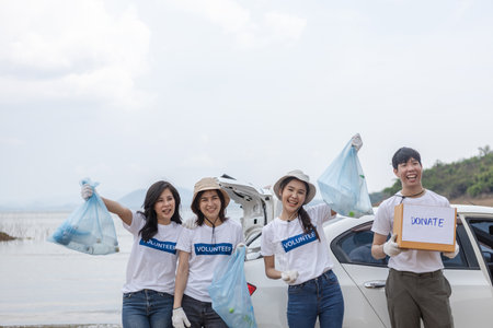 Volunteers holding rubbish bags and Donate box. clean up garbage in tourist attractions. young man holding donation box to contribute garbage collection volunteer project in nature and tourism.の写真素材