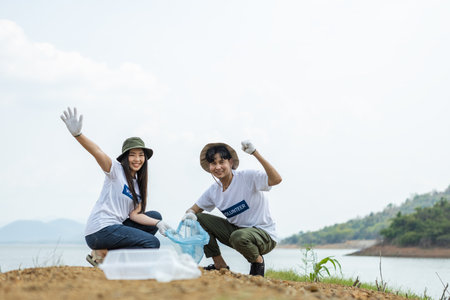 Happy cheerful asian male and female volunteers show hand and collecting garbage, saving world reducing global warming, Volunteers clean plastic bag waste in natural attractions.の写真素材