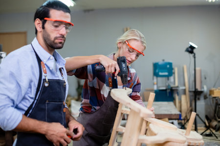 Female carpenter wear goggles using woodworking drill to make furniture. carpenter woman using electric drill machine at workplace.の写真素材