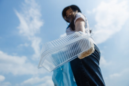 Close up Plastic box garbage in hand female volunteers, conducting environmental cooperation, saving world reducing global warming, Clean plastic bag waste in natural attractions.の写真素材