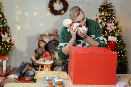 Christmas day concept. handsome man sitting surprised and opening gift box with christmas tree background. Festive atmosphere party.の写真素材