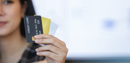 Female holding credit card. Beautiful smiling showing credit card to online payment. Paying online instead of cash via credit system. Money electronic of banking.の写真素材