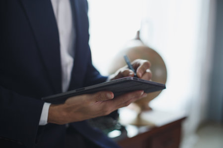Closeup of digital tablet, successful businessman pointing typing touchpad working at office.の写真素材