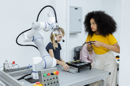 Girl with afro hairstyle wear yellow T-shirt using joystick control smart robotics arm at class room. electric system skill training. Robotics learning innovation. STEM education concept.の写真素材