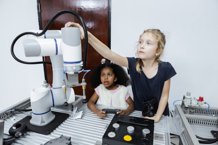 Children girl caucasian using joystick and girl African American control smart robotics arm at class room. electric system skill training. Robotics learning innovation. STEM education concept.の写真素材